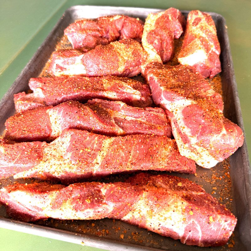 Seasoned pork ribs on a tray ready for the smoker